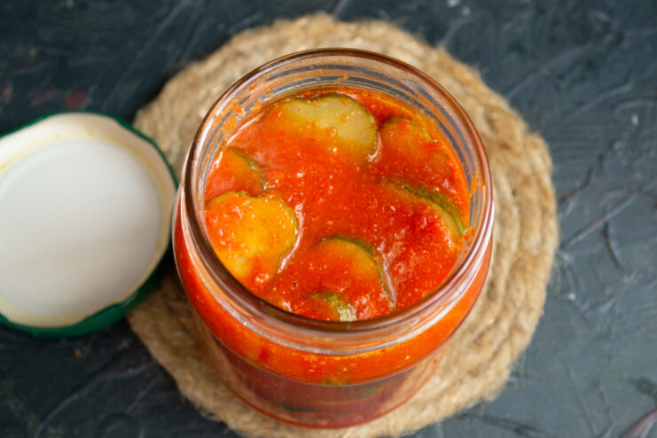 A person ladling hot 'Winter Fairytale' Salad into a clean glass jar.