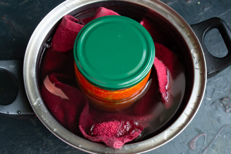 Glass jars of salad submerged in a large pot of boiling water for sterilization.