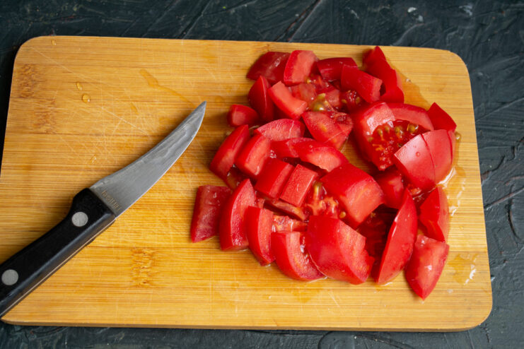 A pile of freshly diced red tomatoes on a cutting board.
