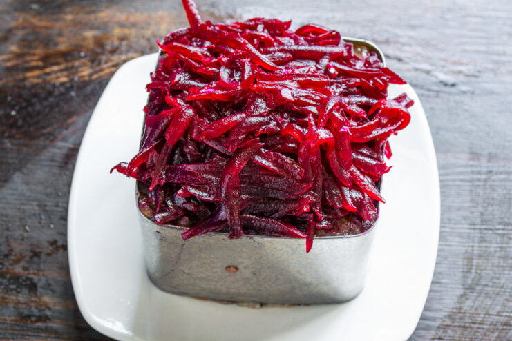 Layering Grated Beets for the 'Fur Coat' Adding a vibrant layer of grated beets over the onion jam in the food ring.
