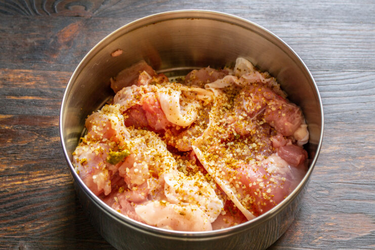 Marinating Chicken with Svanetian Salt and White Wine Chicken pieces in a bowl being seasoned with spices and marinated with white wine.