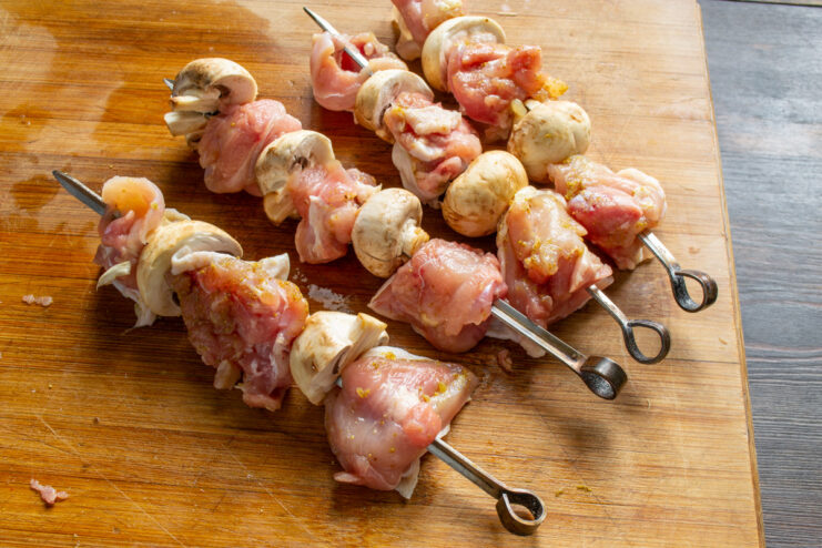 Assembling the Chicken and Mushroom Skewers Threading pieces of marinated chicken and whole mushrooms onto wooden skewers.
