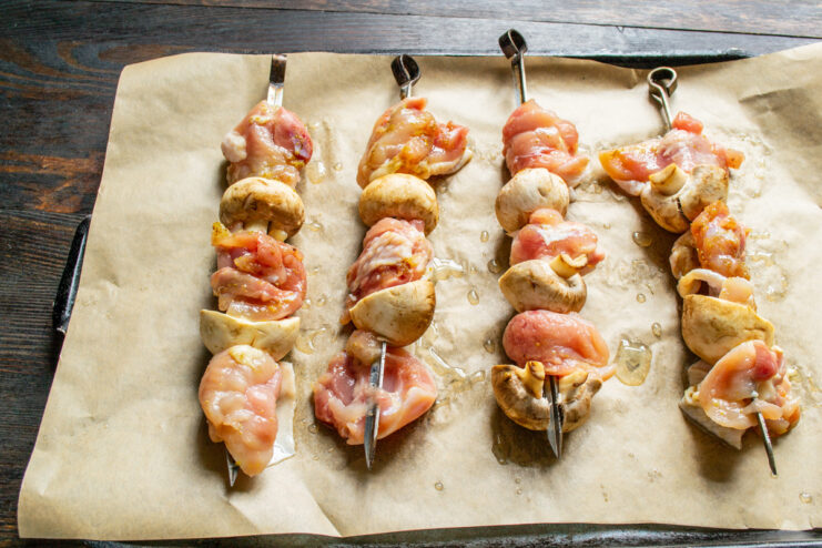 Arranging Skewers on a Baking Sheet for Even Cooking Assembled chicken and mushroom skewers arranged on a parchment-lined baking sheet.