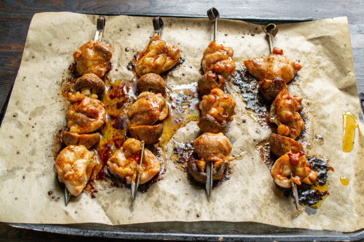 Baking the Chicken Skewers in a Hot Oven A baking sheet with chicken and mushroom skewers being placed into a hot oven.