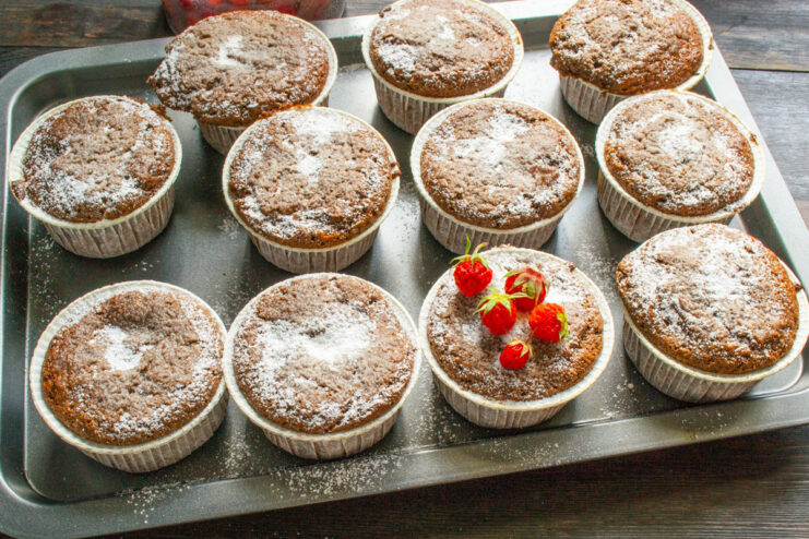 Enjoy your homemade chocolate peach muffins with a hot beverage Finished chocolate peach muffins garnished with fresh berries and powdered sugar, ready to serve.