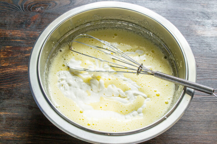 Step 2: Adding sour cream to the egg and sugar mixture Whisking sour cream into the egg and sugar mixture in a glass bowl.