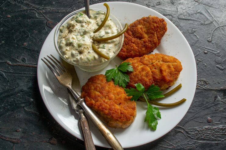 Serving the Deliciously Juicy Kotlety with Tartar Sauce A serving plate with hot, juicy kotlety, a bowl of tartar sauce, and fresh herb garnish.