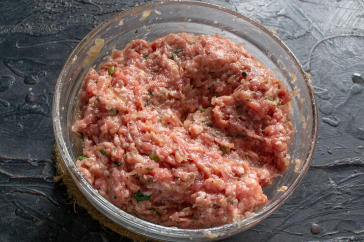 The Secret to Juicy Kotlety: Adding Cold Water Hands mixing ground meat in a bowl with ice-cold water to ensure juicy kotlety.