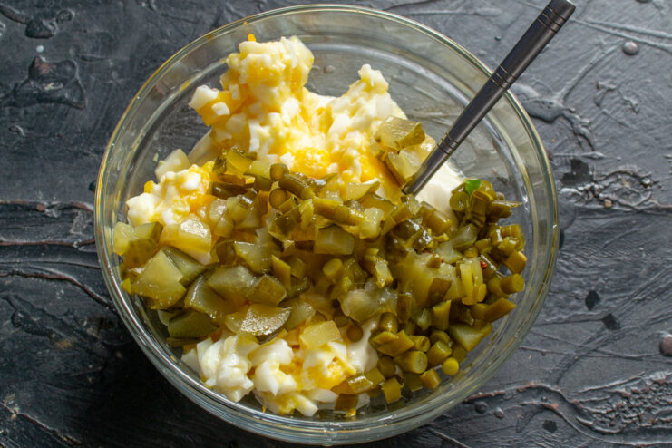 Adding a Tangy Crunch to Tartar Sauce A hand dicing a pickled cucumber on a cutting board to add to the tartar sauce.