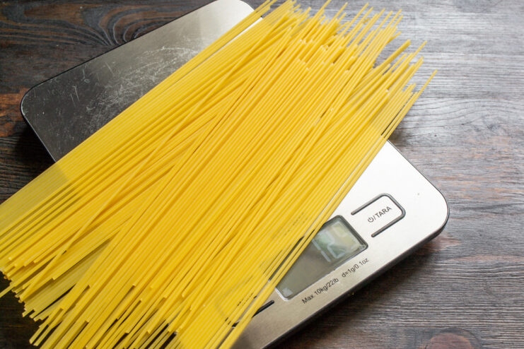 How to Cook Spaghetti Perfectly Al Dente Hand adding a bunch of dry spaghetti into a pot of boiling water.