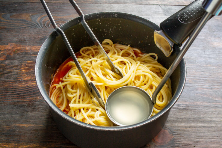 Adding Butter for a Richer, Creamier Sauce A pat of butter melting into the spaghetti and tomato sauce in a pan.