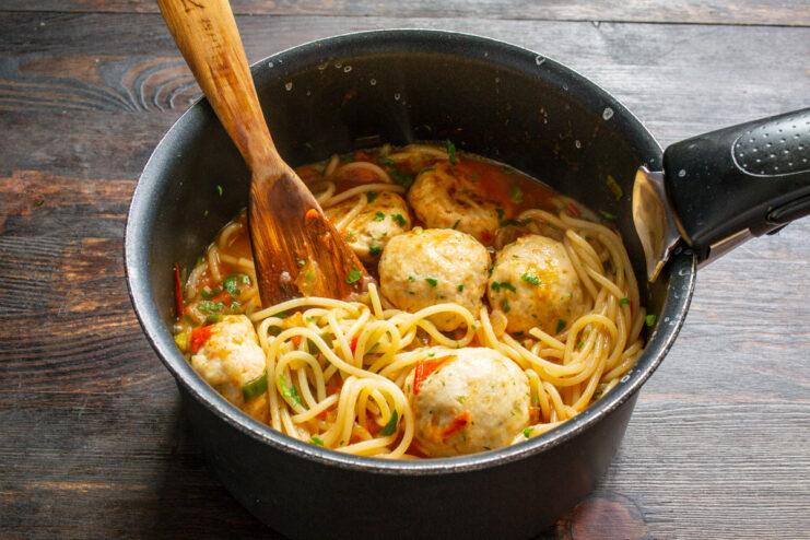 Finishing the Dish by Heating Everything Together Spaghetti, meatballs, and sauce being gently heated and mixed together in a pan.