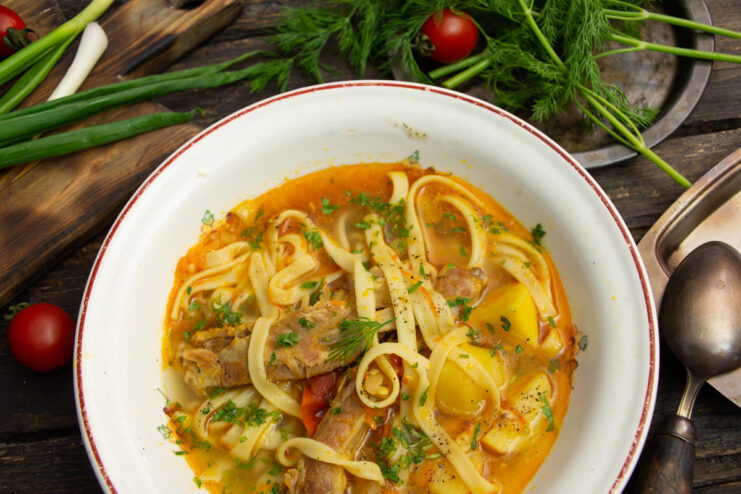 A bowl of finished rib and noodle soup, garnished with fresh parsley.