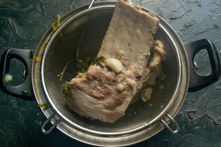 Preparing the tender cooked pork ribs for the soup Cooked pork ribs being separated into individual pieces on a cutting board.
