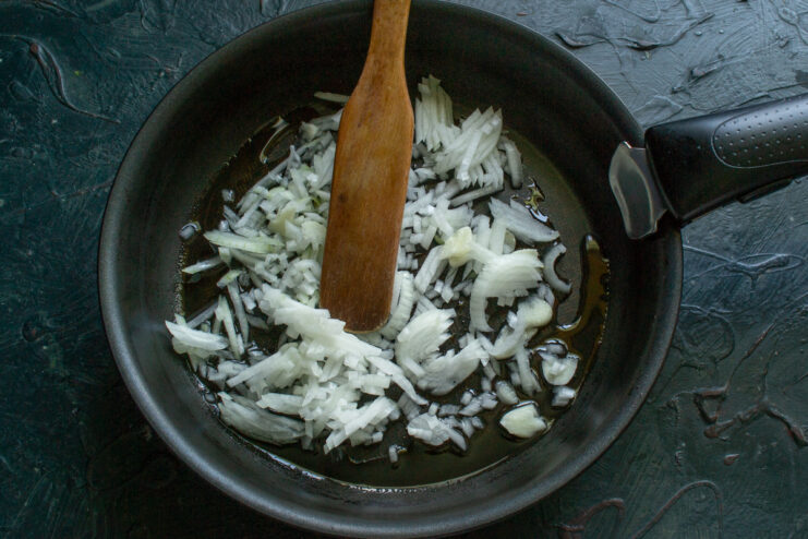 Sautéing onions until soft and translucent for the soup base Chopped onions being sautéed in a frying pan until golden.
