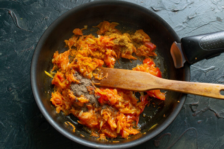 Simmering the vegetable base to meld all the delicious flavors A pan with a simmering vegetable base of onions, carrots, and tomatoes.