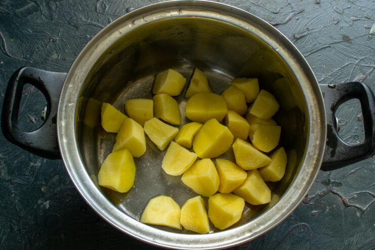 Adding diced potatoes to the soup pot Diced potatoes being added to a large cooking pot.