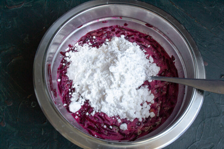 Adding Sugar to the Brownie Mixture Pouring powdered sugar into the mixing bowl with eggs and beetroot.