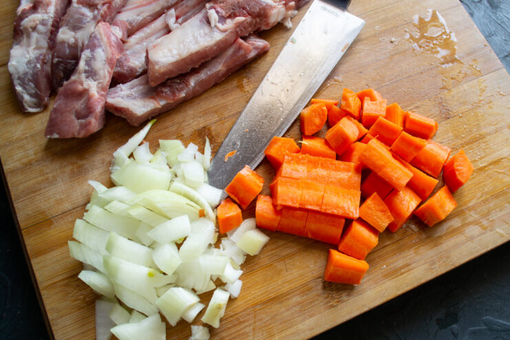 Dicing Vegetables for the Flavor Base A pile of neatly diced yellow onion and bright orange carrots on a cutting board.