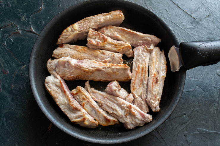 Perfectly Seared Pork Ribs Pork ribs sizzling in a skillet, browned to a perfect golden color on all sides.