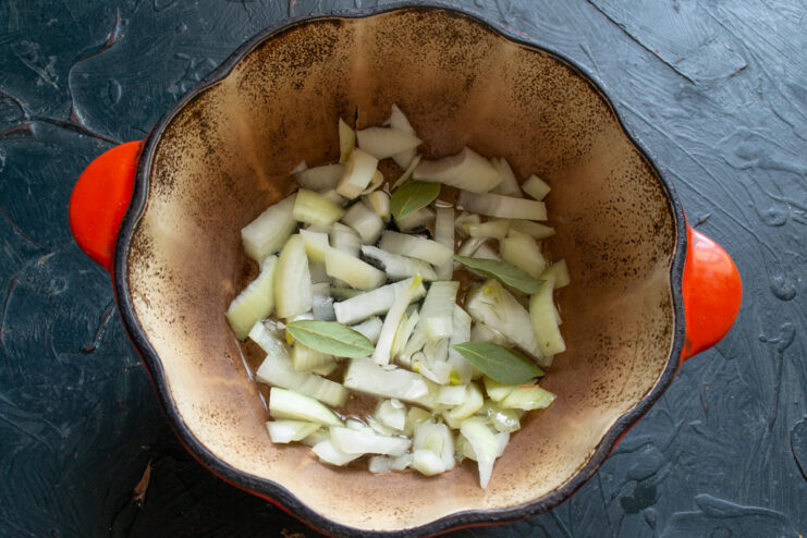 Cooking the Onions Until Translucent Diced onions being cooked in a Dutch oven until soft and translucent.