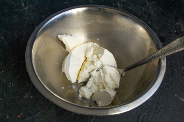 Preparing the Ricotta Base for Syrniki A scoop of fresh ricotta cheese in a clear glass bowl, ready for mixing.