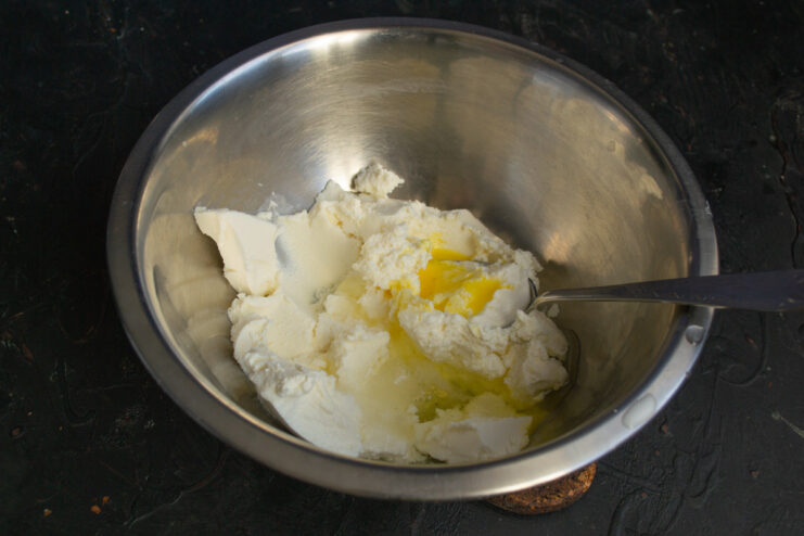 Adding an Egg to the Ricotta Mixture An egg cracked into the bowl with ricotta cheese.