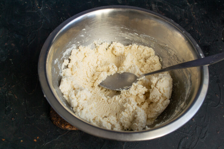 Adding Lemon for a Fresh Flavor Squeezing lemon juice into the syrniki batter in a glass bowl.