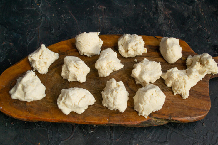 Portioning the Syrniki Dough The ricotta batter divided into small, even portions on a wooden surface.