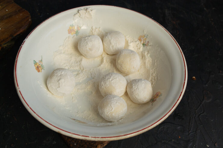 Coating Syrniki in Flour A formed ricotta pancake being coated in a bowl of white flour.