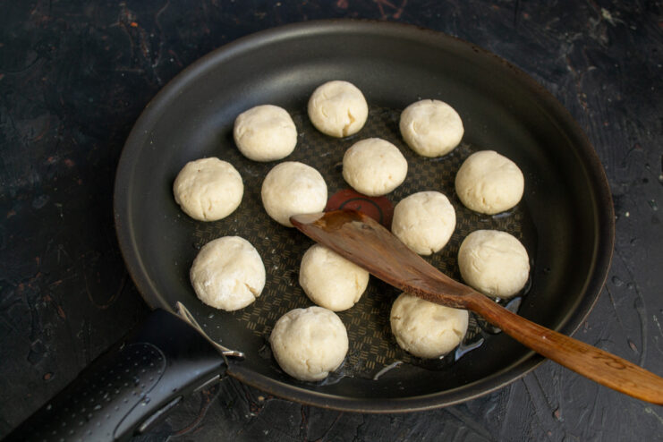 Removing Excess Flour from Syrniki Shaking a sieve with flour-coated syrniki to remove excess flour.