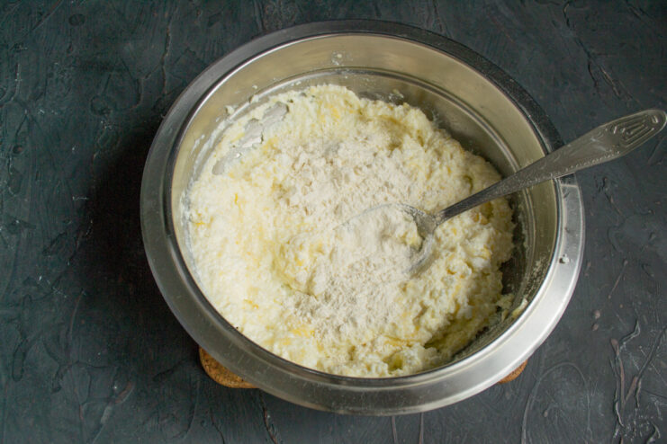 Mixing the Dough and Adding Flour Adding wheat flour to the mixture of farmer's cheese, egg, and banana in a bowl.