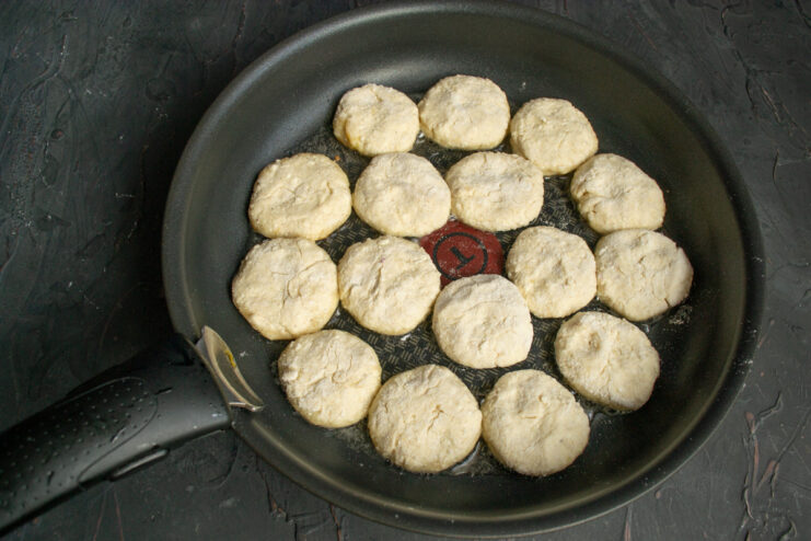 Frying Syrniki in Melted Butter Placing formed syrniki patties into a hot pan with melted butter.