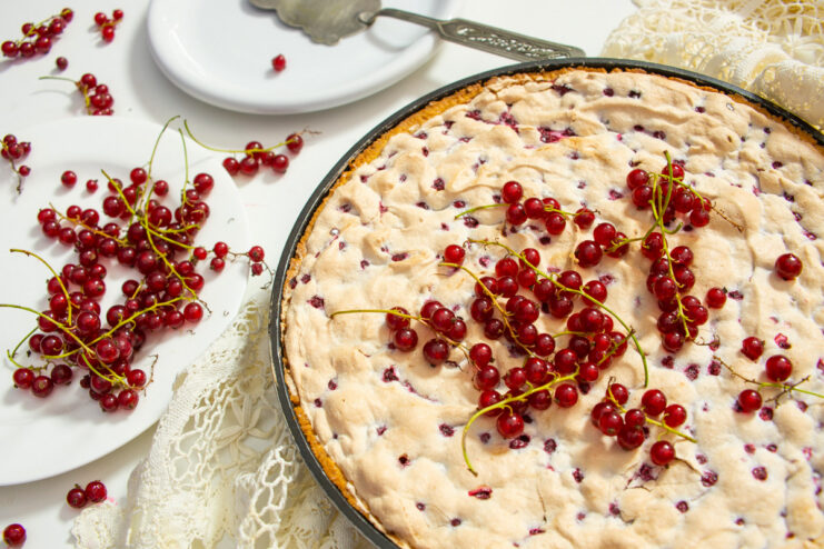A whole baked redcurrant tart with a golden meringue top, presented on a plate.