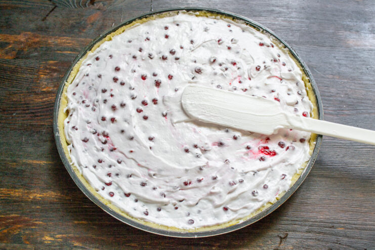 Spreading the Filling into the Tart Shell Spreading the redcurrant meringue filling evenly over the raw pastry in a tart pan.