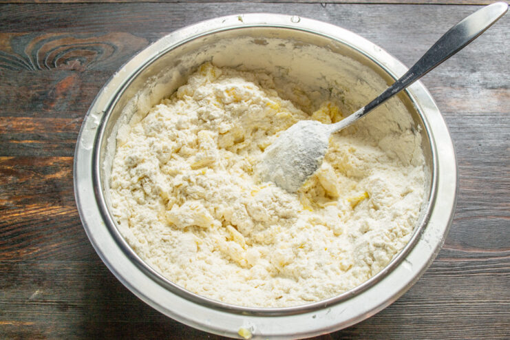 Sifting Dry Ingredients for a Tender Crust Sifting flour and baking powder into a bowl with the butter and egg yolk mixture.
