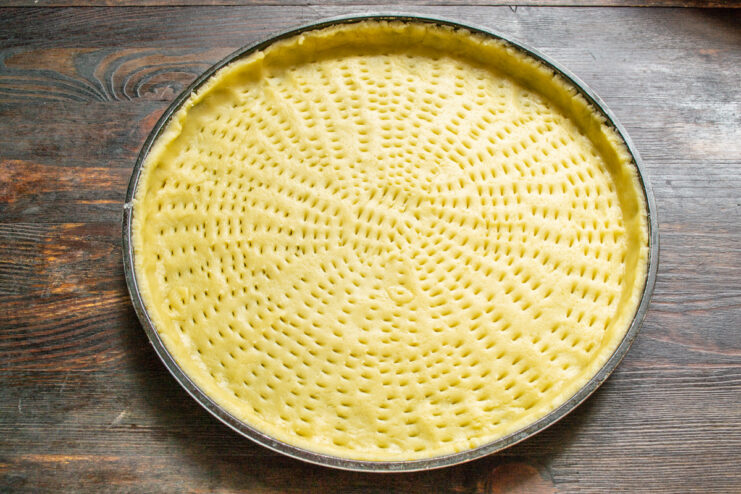 Lining the Tart Pan with Pastry Rolled-out shortcrust pastry being placed into a round tart pan.