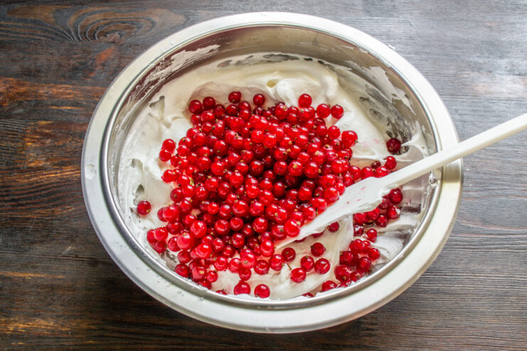 Adding Fresh Redcurrants to the Filling Fresh, dry redcurrants being added to the bowl of meringue filling.