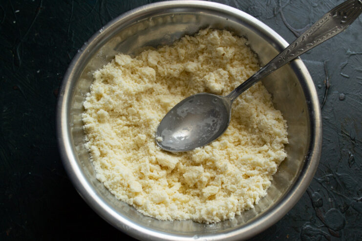 Creating a Sandy Texture for the Pastry Dough Hands rubbing butter into flour in a bowl, creating a breadcrumb-like texture.