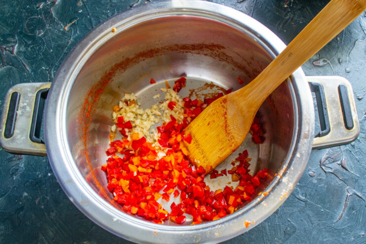 Adding Aromatics: Chopped Garlic, Chili, and Bell Pepper A pot containing finely chopped red bell pepper, chili, and garlic.