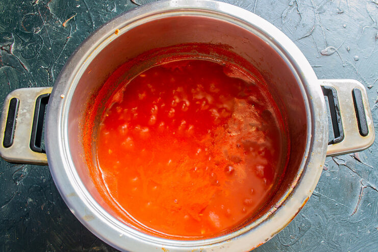 Simmering the Sauce to Thicken and Develop Flavor Thick tomato sauce simmering in a pot on the stove, reducing in volume.
