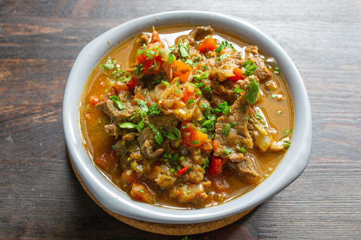 A serving of Thai-style braised beef in a white bowl, garnished with fresh cilantro.