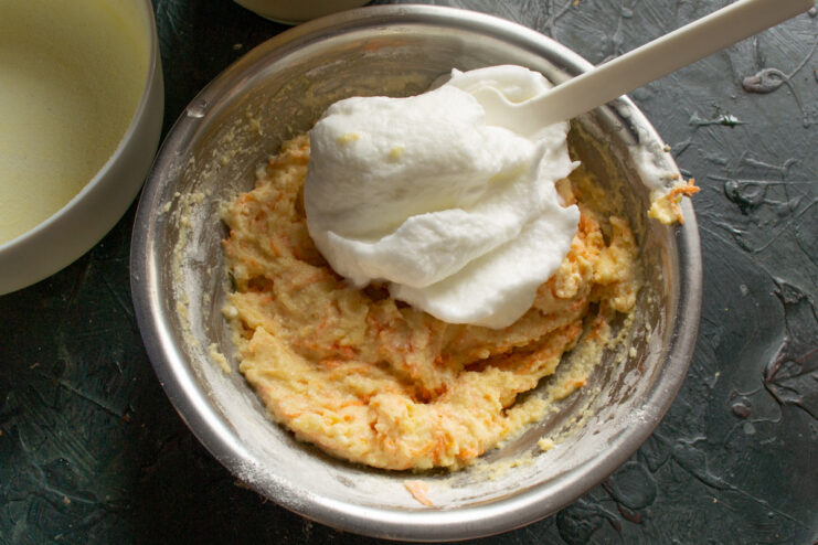 Lightening the Batter with Whipped Egg Whites Folding whipped egg whites into the thick casserole batter with a spatula to lighten it.