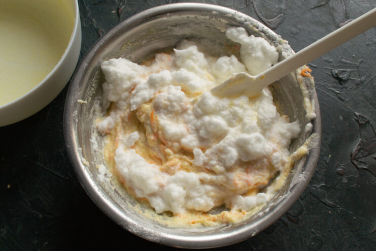 Gently Folding in the Remaining Egg Whites Carefully folding the remaining fluffy whipped egg whites into the batter with a spatula.