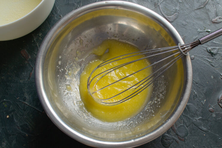 Adding Oil to the Casserole Batter Pouring vegetable oil from a small glass pitcher into the bowl with the egg yolk mixture.