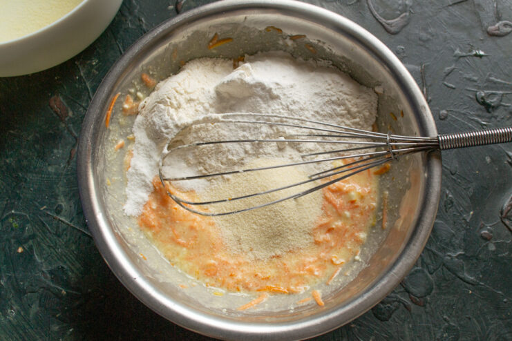Combining Dry Ingredients for the Casserole Adding flour, semolina, and baking powder to the wet ingredients in the mixing bowl.