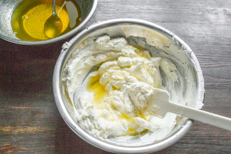 Incorporating the cooled fruit jelly into the mousse Pouring the cooled liquid fruit jelly into the white creamy cheese and cream mixture.