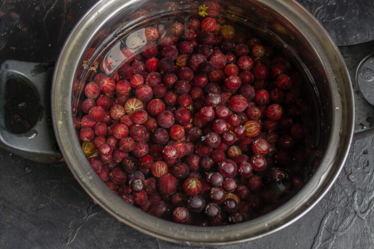 Prepared red gooseberries soaking in a bowl of cold water.
