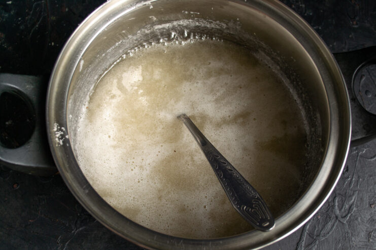 Sugar syrup boiling in a saucepan on the stove.