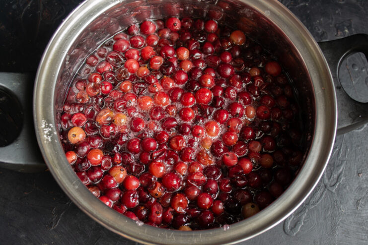 Gooseberry jam simmering in a saucepan on the stove.